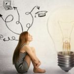 woman sitting in front of light bulb thinking has many thoughts life ideas